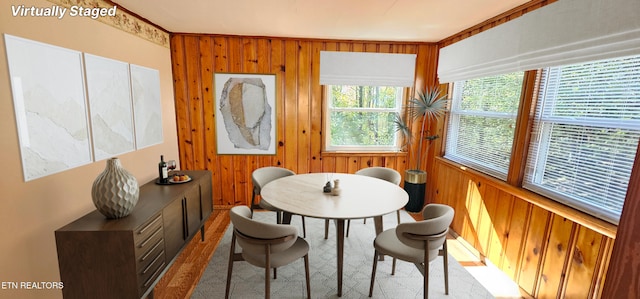 carpeted dining space with crown molding and wood walls