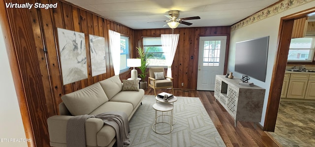 living room featuring a wealth of natural light, sink, wooden walls, and dark hardwood / wood-style floors