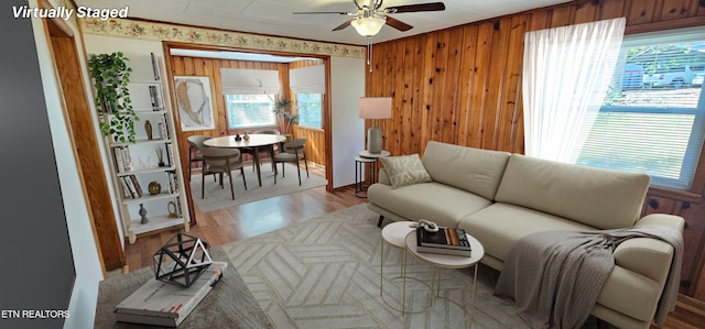 living room featuring wooden walls, light hardwood / wood-style floors, and ceiling fan