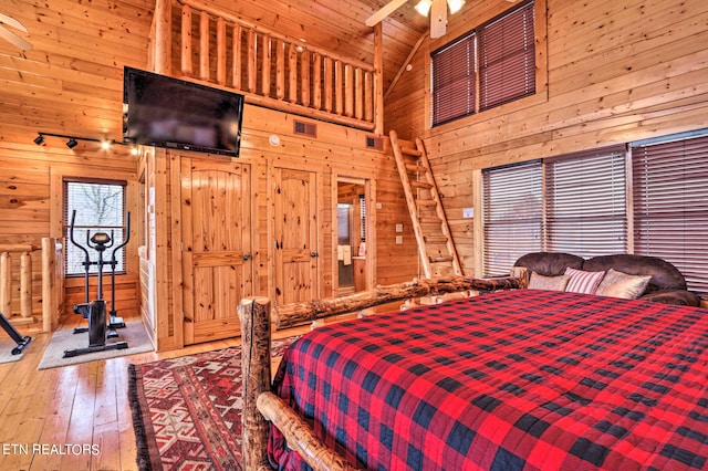 bedroom featuring high vaulted ceiling, wood walls, wooden ceiling, beam ceiling, and hardwood / wood-style floors