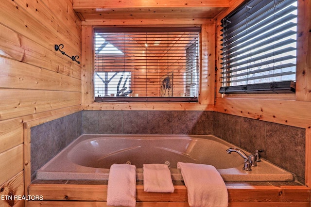 bathroom featuring wood walls and a bath