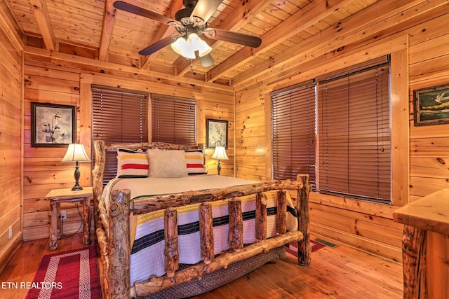 bedroom with wood ceiling, beamed ceiling, wooden walls, hardwood / wood-style floors, and ceiling fan