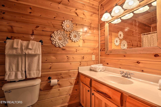 bathroom with wood walls, toilet, vanity, and a shower with curtain