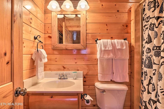 bathroom featuring walk in shower, wooden walls, vanity, and toilet