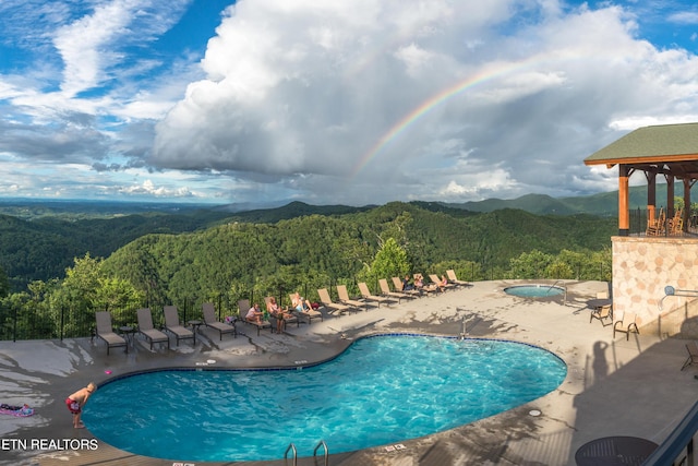 view of pool with a mountain view, a patio area, and a hot tub