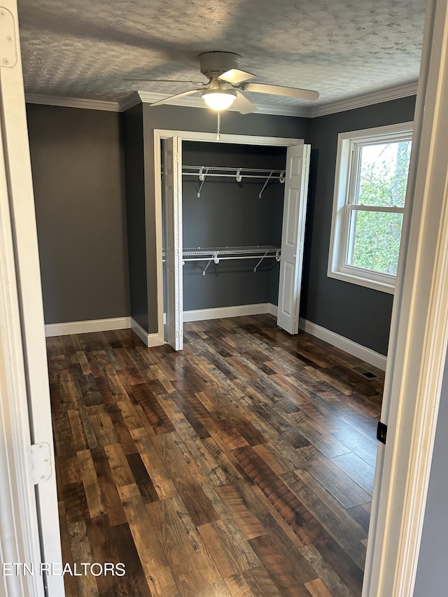 unfurnished bedroom with ornamental molding, dark hardwood / wood-style flooring, ceiling fan, and a closet