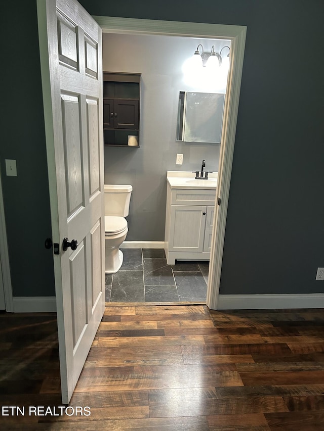 bathroom with wood-type flooring, vanity, and toilet