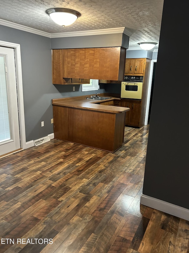 kitchen featuring white oven, a textured ceiling, kitchen peninsula, and dark hardwood / wood-style flooring