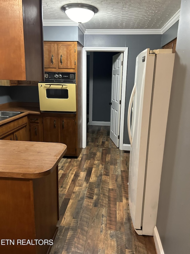 kitchen with sink, crown molding, dark hardwood / wood-style flooring, and white appliances