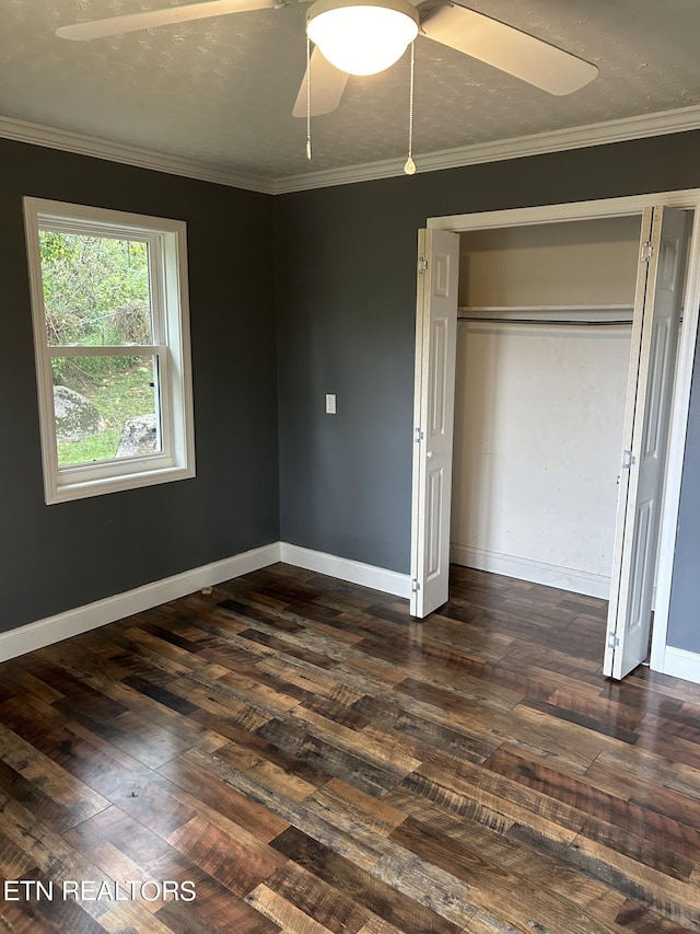 unfurnished bedroom with ceiling fan, a closet, crown molding, and dark hardwood / wood-style flooring