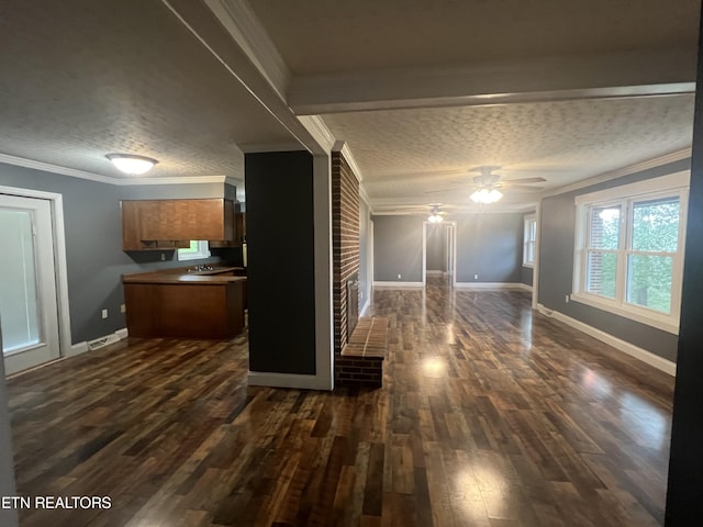 interior space featuring ceiling fan, ornamental molding, a brick fireplace, a textured ceiling, and dark hardwood / wood-style flooring