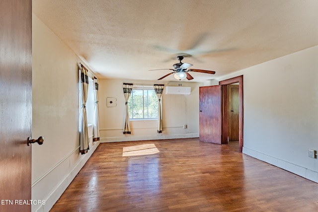 unfurnished room with ceiling fan, a textured ceiling, hardwood / wood-style floors, and an AC wall unit