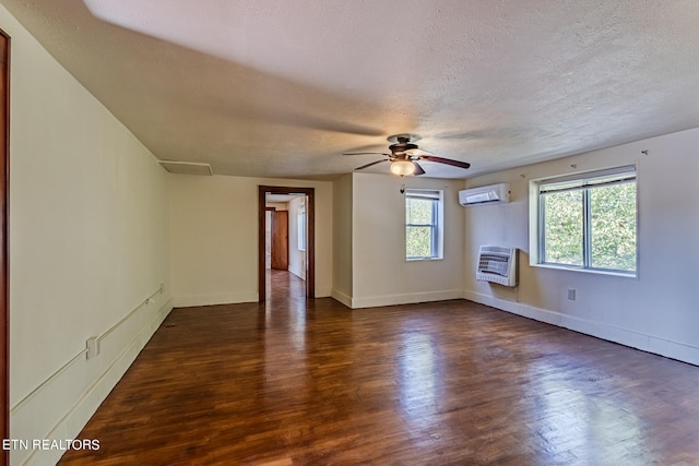 empty room featuring heating unit, a textured ceiling, ceiling fan, a wall unit AC, and dark hardwood / wood-style floors