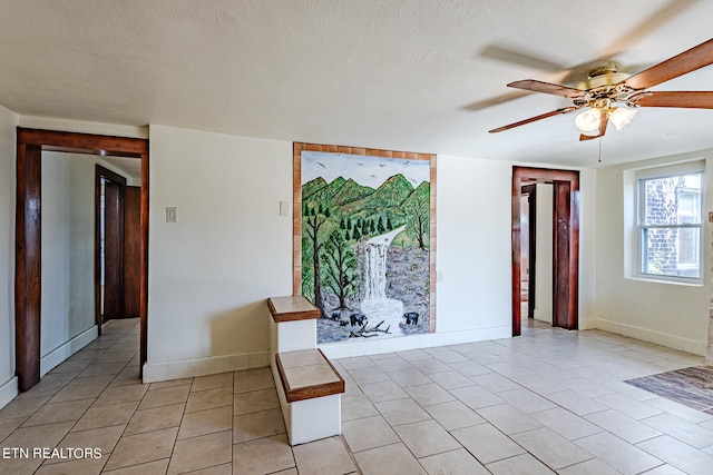 tiled empty room featuring a textured ceiling and ceiling fan