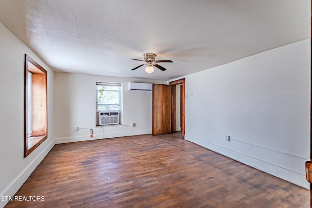 spare room with ceiling fan, cooling unit, a wall mounted AC, a textured ceiling, and dark wood-type flooring