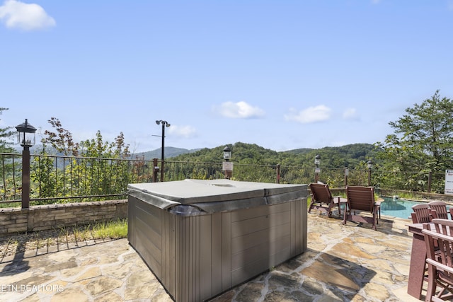 view of patio with a mountain view and a pool with hot tub