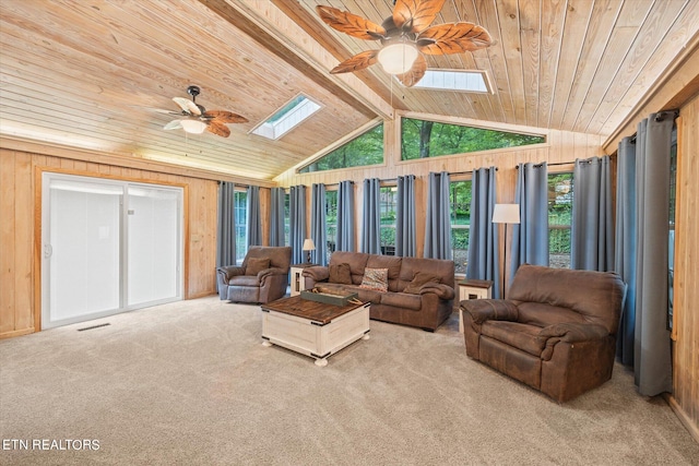 carpeted living room with wooden walls, ceiling fan, wooden ceiling, and vaulted ceiling with skylight