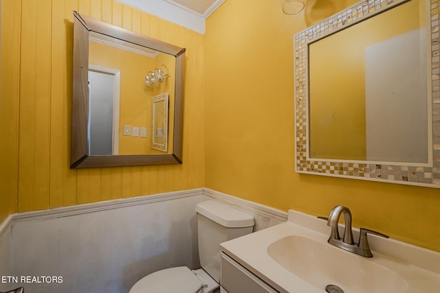 bathroom with ornamental molding, vanity, wood walls, and toilet