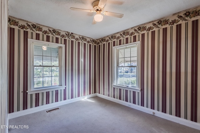 empty room with ceiling fan, carpet flooring, and a textured ceiling