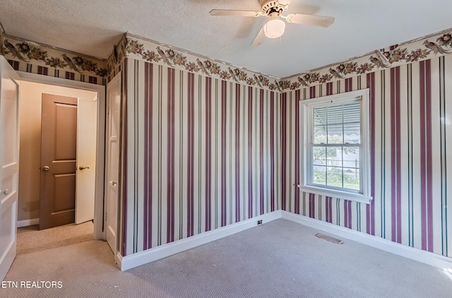 carpeted spare room with ceiling fan and a textured ceiling