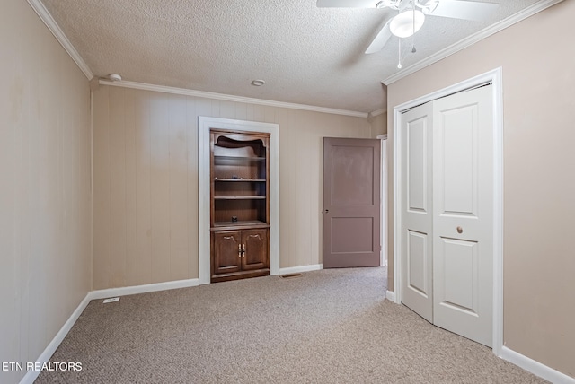 unfurnished bedroom with a textured ceiling, ornamental molding, light carpet, and ceiling fan