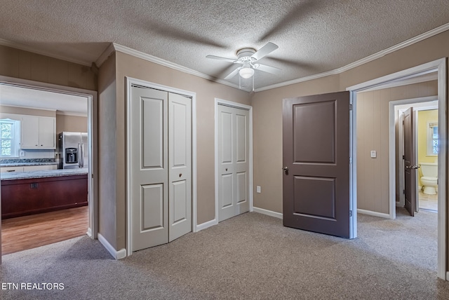 unfurnished bedroom featuring ornamental molding, connected bathroom, ceiling fan, and stainless steel fridge