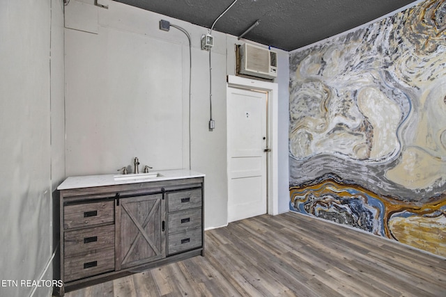 bathroom featuring a textured ceiling, vanity, a wall unit AC, and hardwood / wood-style flooring