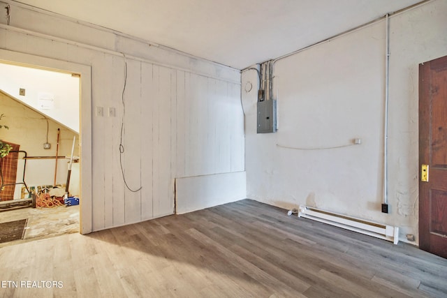 basement featuring a baseboard heating unit, electric panel, and hardwood / wood-style flooring