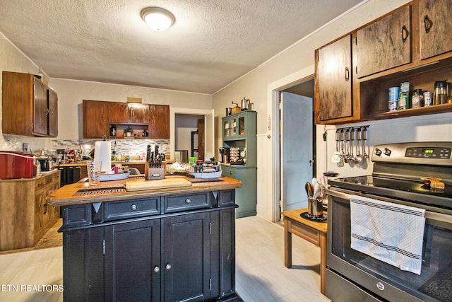 kitchen featuring backsplash, stainless steel electric range oven, and a textured ceiling