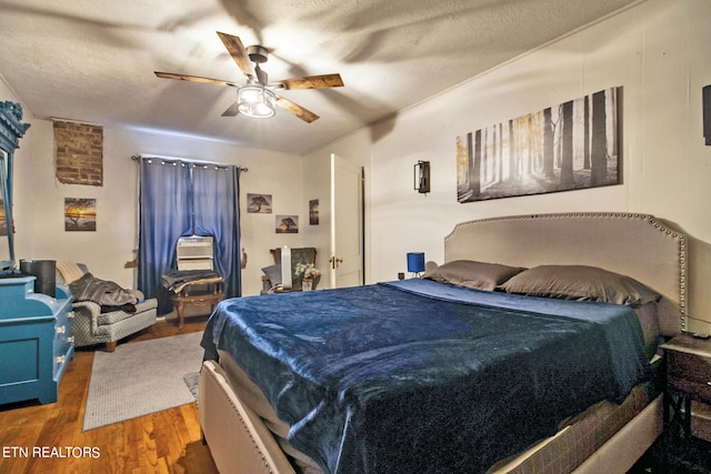 bedroom with a textured ceiling, ceiling fan, and dark hardwood / wood-style flooring