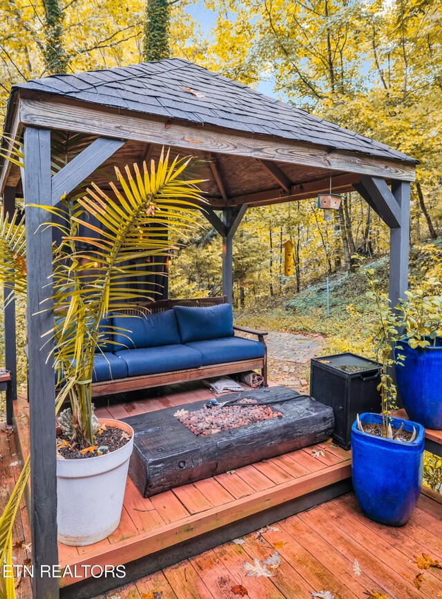 wooden terrace with a gazebo and an outdoor living space with a fire pit