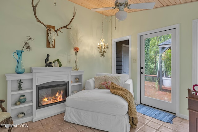 sitting room with ceiling fan with notable chandelier, vaulted ceiling, and light tile patterned floors