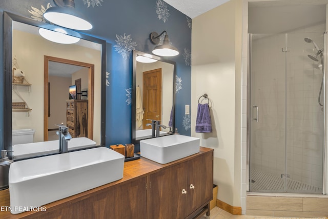 bathroom with a shower with door, vanity, tile patterned flooring, and toilet