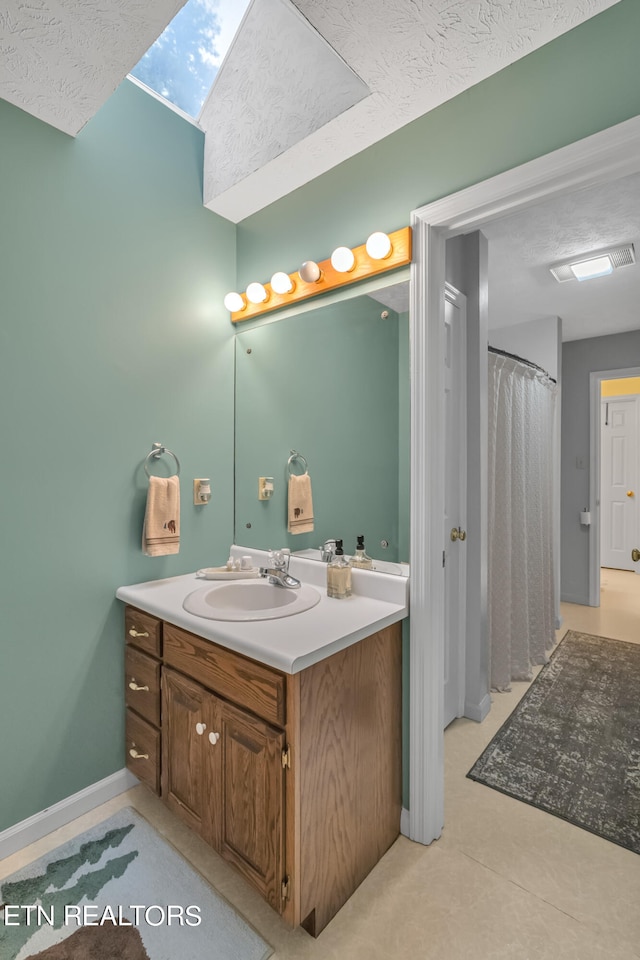 bathroom with vanity, a textured ceiling, and a skylight