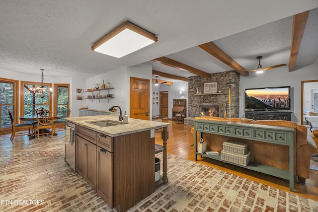 kitchen featuring dishwasher, sink, ceiling fan with notable chandelier, and a kitchen island with sink