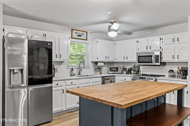 kitchen with ceiling fan, sink, light hardwood / wood-style flooring, white cabinetry, and stainless steel appliances