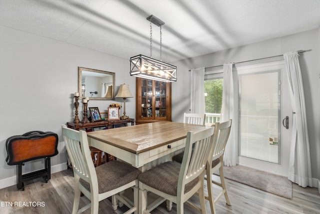 dining area with light hardwood / wood-style flooring, a textured ceiling, and an inviting chandelier