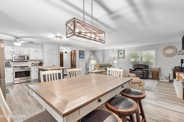 dining room with ceiling fan, a textured ceiling, and light hardwood / wood-style flooring