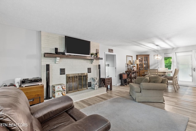 living room featuring a textured ceiling, light hardwood / wood-style floors, and a brick fireplace