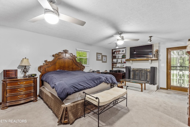 carpeted bedroom featuring a textured ceiling, ceiling fan, and a brick fireplace