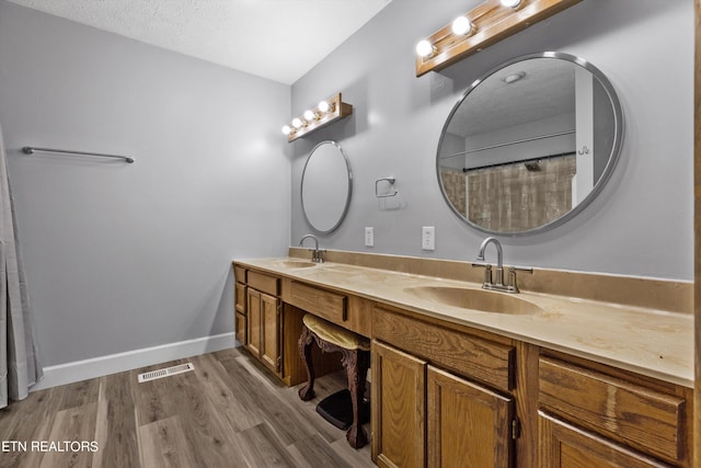 bathroom featuring wood-type flooring, vanity, a textured ceiling, and a shower with shower curtain