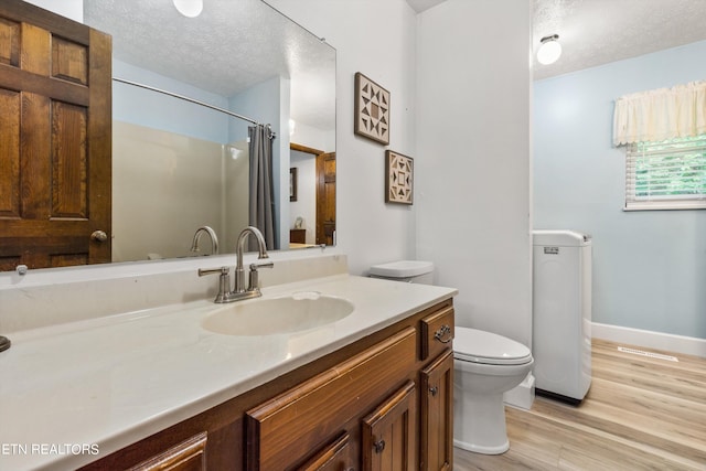 bathroom with vanity, a textured ceiling, wood-type flooring, a shower with shower curtain, and toilet