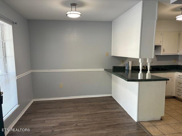 kitchen with white cabinetry, kitchen peninsula, and dark hardwood / wood-style flooring