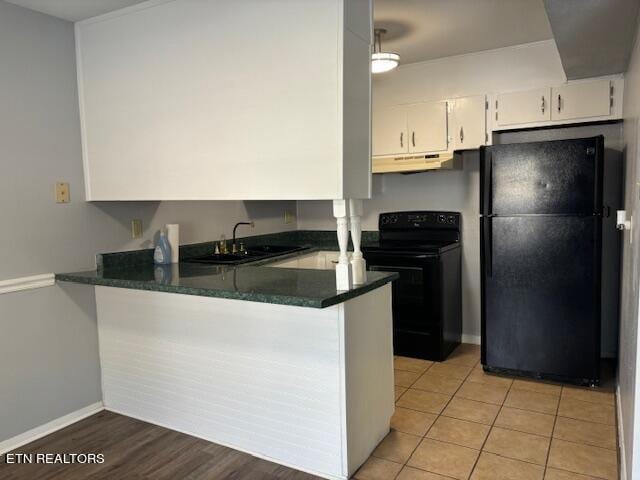 kitchen with light tile patterned flooring, white cabinets, kitchen peninsula, black appliances, and sink