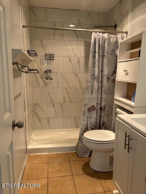 bathroom featuring tile patterned flooring, walk in shower, vanity, and toilet