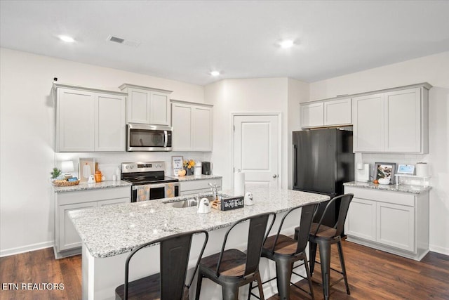 kitchen featuring appliances with stainless steel finishes, sink, an island with sink, and dark hardwood / wood-style flooring