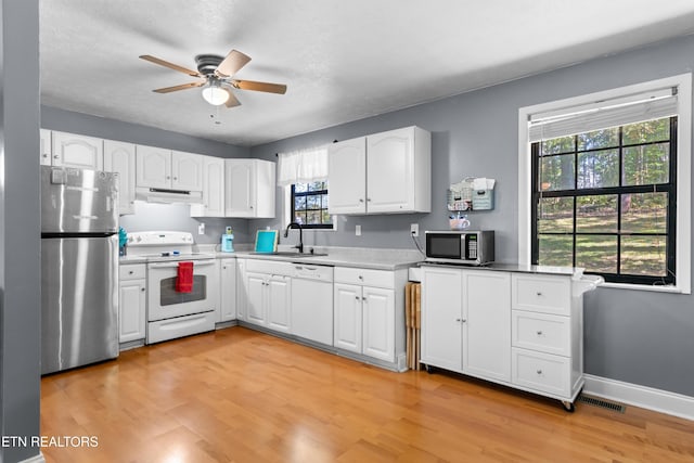 kitchen with stainless steel appliances, white cabinetry, sink, and a healthy amount of sunlight