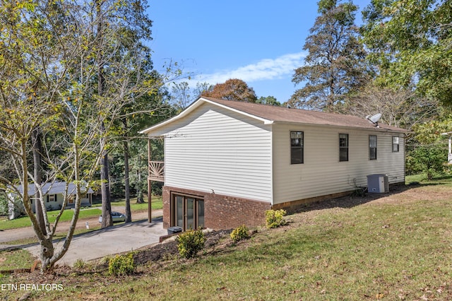 view of side of property featuring central AC and a lawn