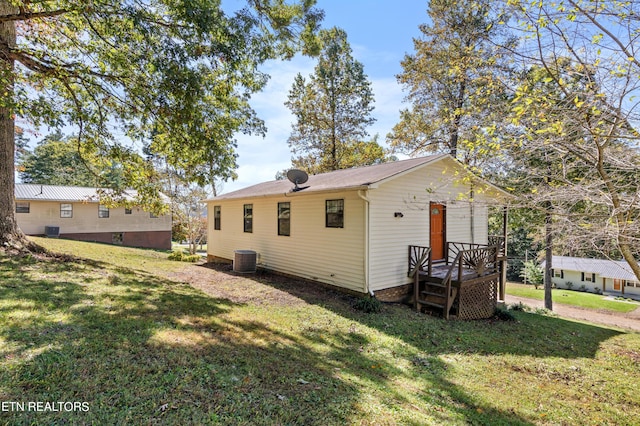 back of house featuring central AC unit and a lawn