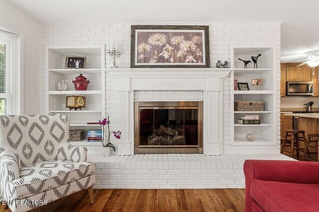 sitting room featuring wood-type flooring, ceiling fan, and a fireplace